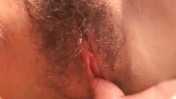 En brunette med lange ben bøjet forover af kræft og indrammet sin seksa lietas behårede fisse af kærlighed.